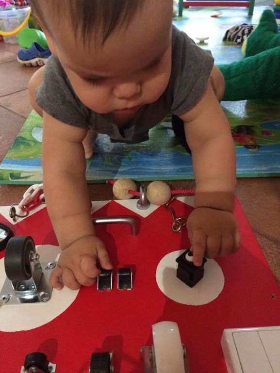 a one year old baby playing with a bright activity board