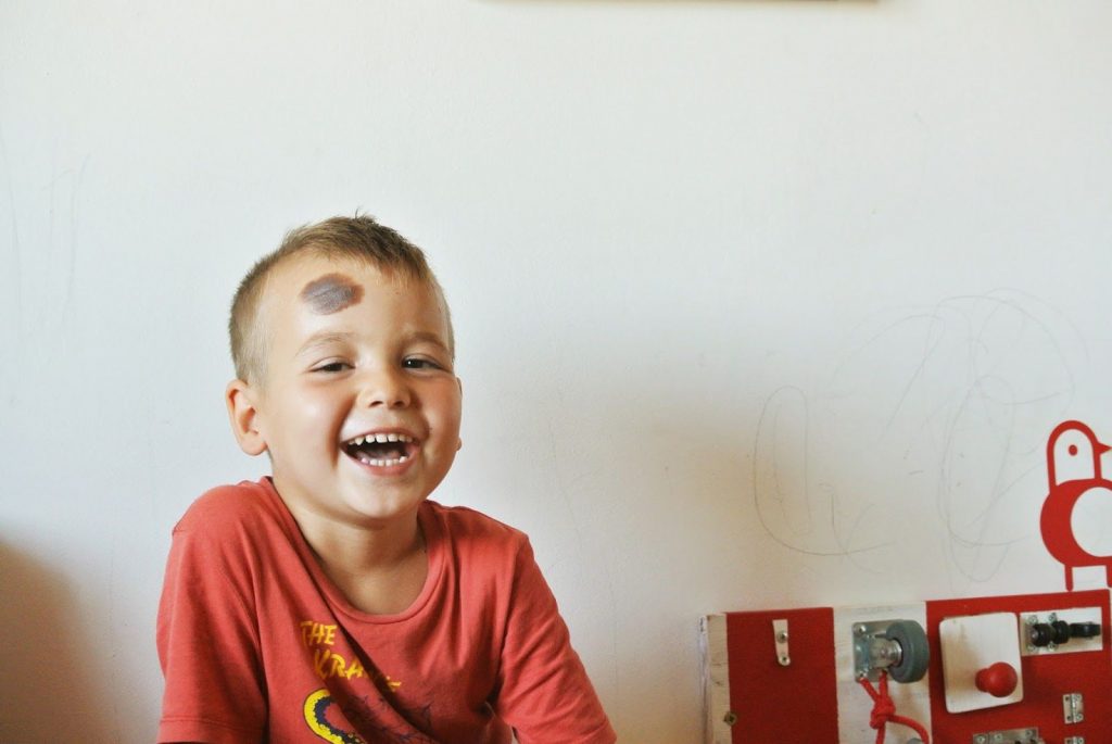 little kid next to bright red busy board