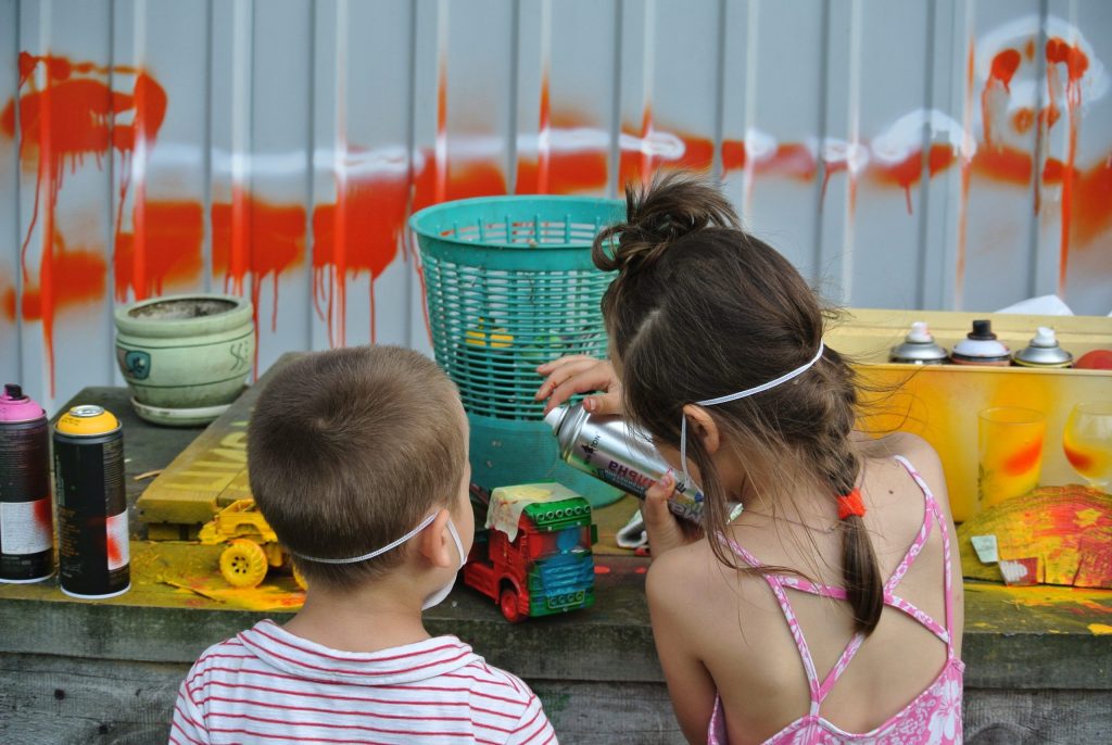 young boy and girl playing with the paint spray cans